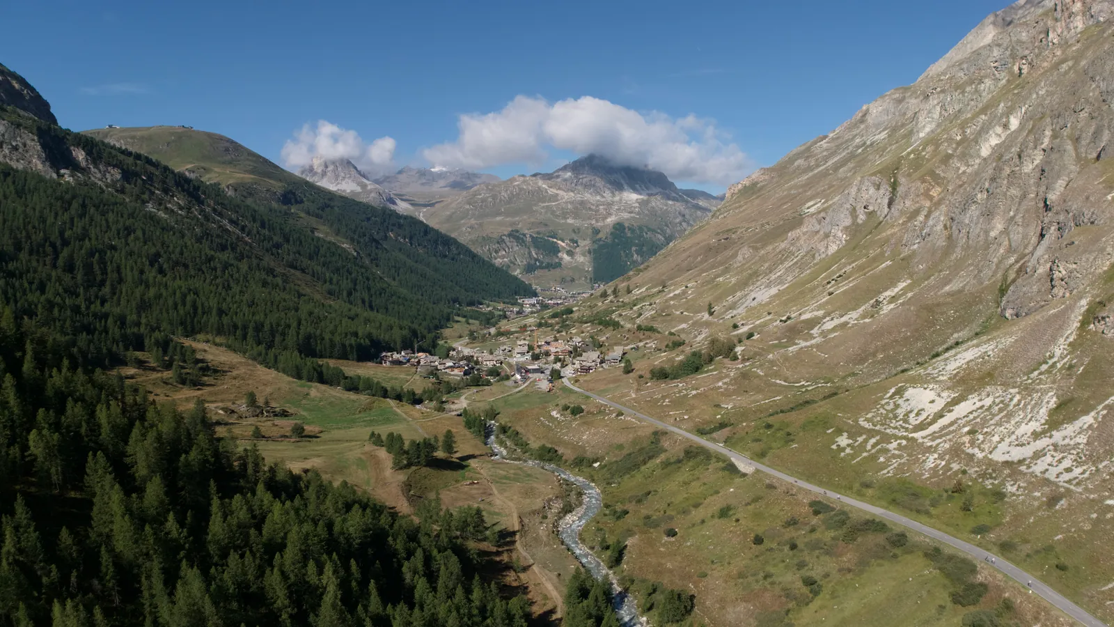 Valle alpino con un río y una carretera
